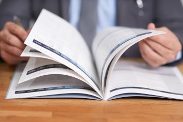 Cropped shot of business man at a desk flicking through a prospectus or brochure