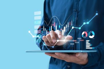 A person interacts with a tablet displaying futuristic data visuals, including graphs and charts, symbolising digital analytics and growth.