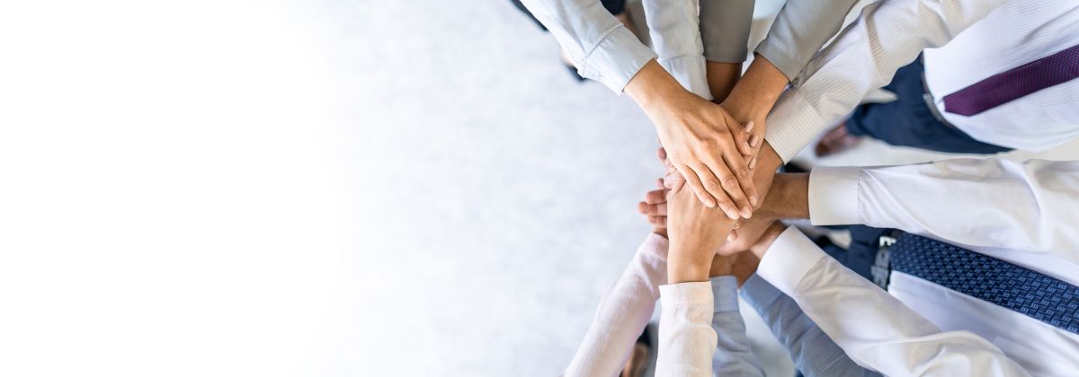 Group of diverse, business people with arms centred showing unity and teamwork.